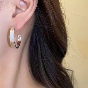 Primo piano di orecchini a cerchio a C spazzolati indossati, texture opaca elegante