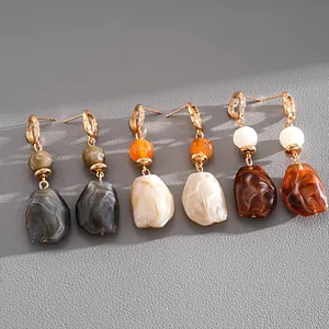 Macro view of retro irregular resin stone-like drop earrings in various earthy colors.