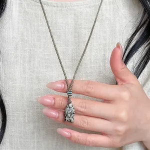 Close-up of vintage braided rope necklace with spotted fish pendant and heart detail