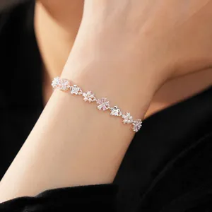 Détail d'un bracelet en argent avec des fleurs en zircon rose et des perles au poignet