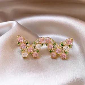 Dettaglio di eleganti orecchini a farfalla con zirconi rosa e bianchi su seta liscia.