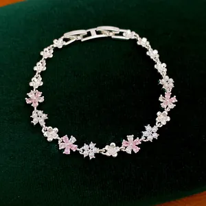 Vue détaillée d'un bracelet fleurs en zircon rose et perles sur velours vert