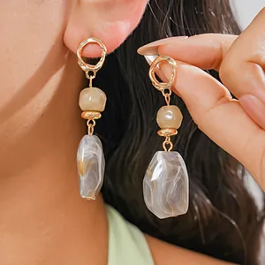 Close-up of vintage resin drop earrings with grey marble pattern and gold metal