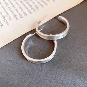 Dettaglio macro di orecchini a lobo a forma di C in argento spazzolato su libro
