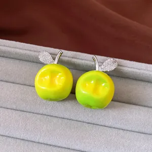 Detailansicht der grünen Apfel-Ohrringe mit kristallbesetzten Blättern auf Schmucktablett.