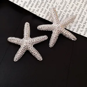 Detailed macro view of silver-toned starfish ear studs with textured zircon pavé.