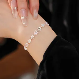 Gros plan d'un bracelet élégant avec fleurs en zircon et perles sur un poignet.