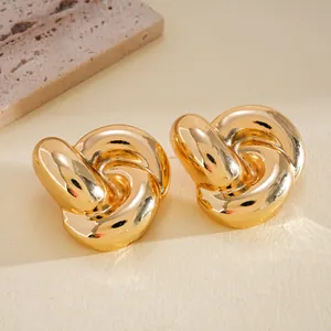 Macro detail of polished gold-toned knot stud earrings showing high-quality shine