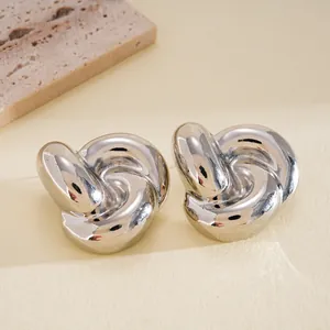 Detailed macro shot of elegant polished silver twisted knot stud earrings on neutral background