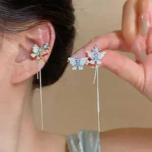Détail d'un élégant clip d'oreille papillon bleu avec de longs glands délicats.