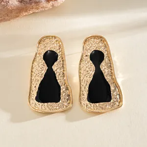 Close-up of vintage gold hammered earrings with black enamel center detail
