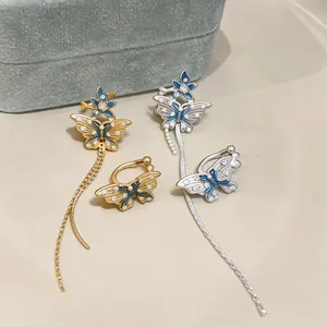 Gros plan de clips d'oreilles papillon et fleur avec zircons et émail bleu.