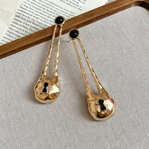 Detail shot of vintage gold-tone earrings with black studs and keyhole pendant