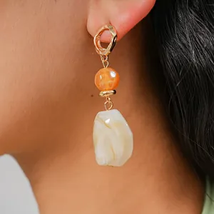 Detailed view of irregular geometric resin pendant earring with marbled texture on model