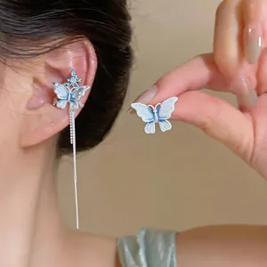 Détail d'un protège-oreille papillon bleu et blanc avec un long gland en argent.