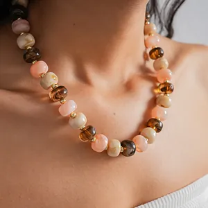 Detailed view of women's acrylic marbled bead necklace with peach and brown tones.