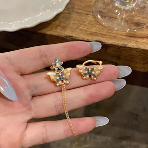 Détail de boucles d'oreilles papillon dorées avec émail bleu et pompons zircons