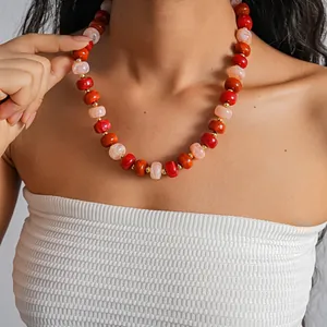 Close-up of vibrant red and orange acrylic swirled bead necklace worn on neck by a model