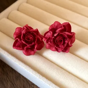 Detailed close-up of elegant red rose flower stud earrings on velvet jewelry display