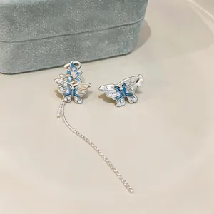 Gros plan de boucles d'oreilles papillon et fleur en zircon avec chaîne à pampilles.