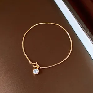 Close-up of 18k gold plated snake chain bracelet featuring a round zircon stone charm