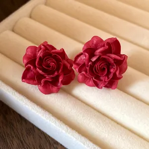 Close-up macro shot showing the intricate red rose petals of these elegant floral stud earrings.