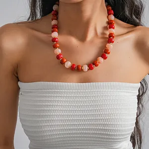 Close-up detail of a vibrant red and orange marbled acrylic round bead necklace on model