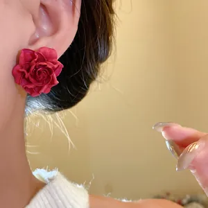 Close-up detail of vintage elegant red rose floral stud earrings worn on a model's ear