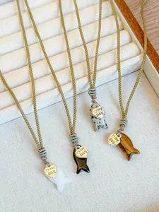 Detail view of woven rope necklaces with stone fish pendants and engraved heart charms
