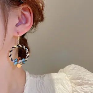 Nahaufnahme von eleganten, goldfarbenen Strass-Kristall-Creolen an einem Modelohr.