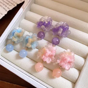 Orecchini a perno a fiore in resina pastello con perle in un portagioie bianco