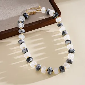 Detail of marbled acrylic round bead necklace with gold spacers on wooden tray.