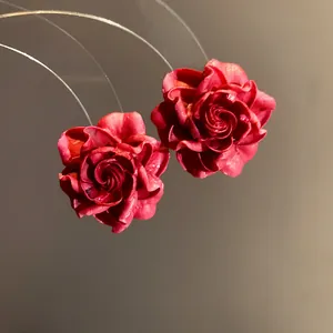 Close-up detail of elegant vintage style red rose flower earrings with textured petals