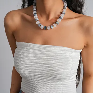 Close-up of marble patterned acrylic bead necklace on a model wearing a white top