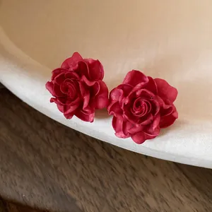 Detailed macro view of vintage red rose stud earrings with delicate petal textures.