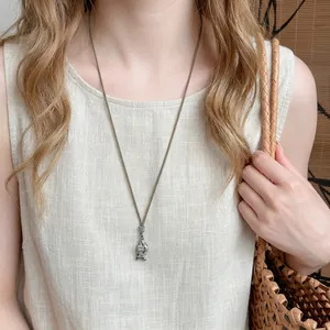 Detail view of the retro style fish pendant with heart engraving on a brown woven rope chain.