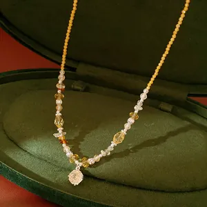 Detail view of a zircon flower pendant beaded necklace in a green velvet jewelry box