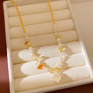 Close-up detail of yellow beaded necklace with a clear faceted zircon flower pendant