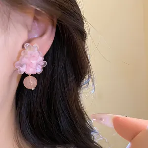 Primo piano di un elegante orecchino a fiore in resina rosa con ciondolo a perla