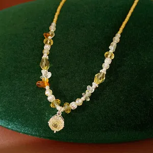Detail view of a handcrafted stone bead necklace with a dainty zircon flower charm.