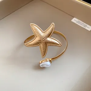 Detailed close-up showing a vintage gold starfish armlet accented with a white pearl.