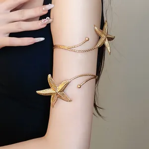 Detailed close-up of a stylish golden metal starfish armlet wrap bracelet worn on a woman's arm