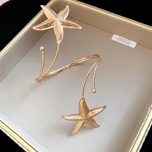 Detailed close-up of a golden starfish upper arm cuff featuring a textured metallic finish.