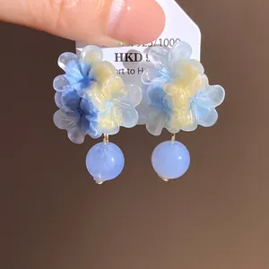 Vista dettagliata di eleganti orecchini a fiore in resina blu con pendenti a sfera