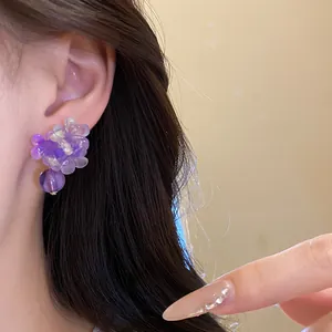 Dettaglio ravvicinato di un orecchino a fiore in resina viola con ciondolo a perla tonda.