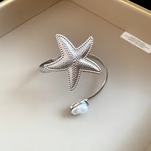 Detailed view of a silver textured starfish arm ring with an elegant pearl accent.