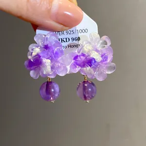 Dettaglio di orecchini a fiore in resina viola con petali cangianti e perline
