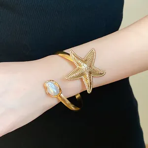 Close-up detail of vintage gold metal starfish arm cuff with an irregular pearl accent