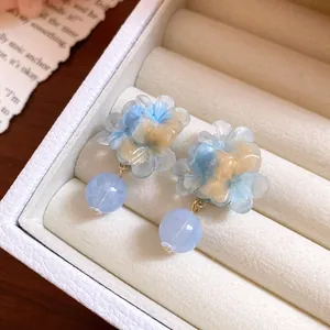 Dettaglio di orecchini a fiore in resina con perle marmorizzate blu in scatola