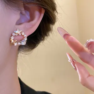 Close-up of elegant 18k gold plated butterfly stud earrings with pearls and zircons